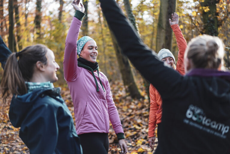 Pace-Training im Herbst: Laufgruppe feiert Erfolg mit erhobenen Armen im Wald