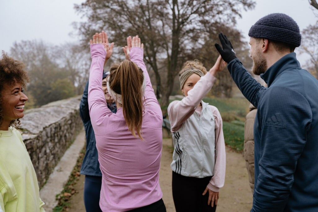 Pace und Herzfrequenz beim Laufen – Läufergruppe gibt sich High-Fives nach dem Training, gemeinsame Freude über erreichte Ziele