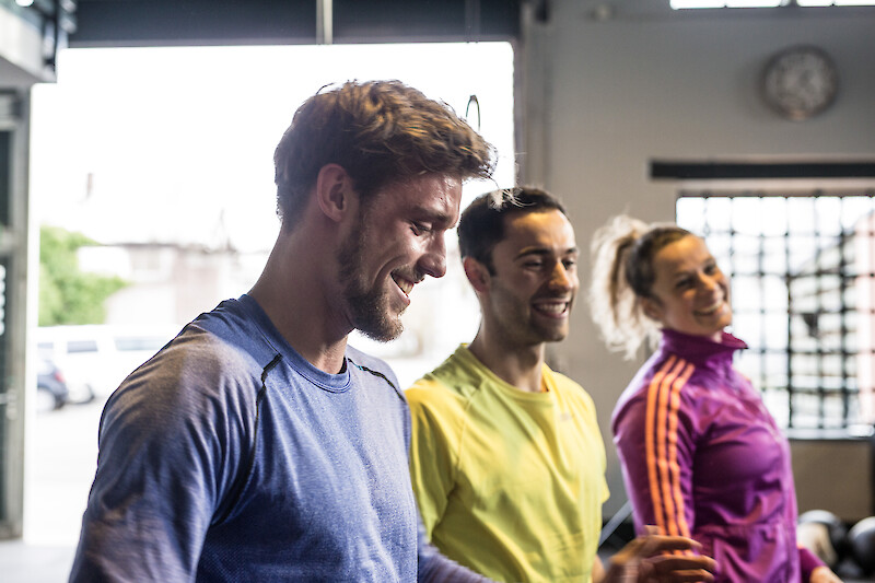 Motivierte Gruppe beim Zirkeltraining mit Spaß und Teamgeist auf dem Weg zum Abnehmen