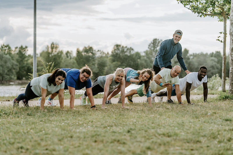 Gruppe trainiert gemeinsam im Freien – Zirkeltraining zuhause mit abwechslungsreichen Ganzkörperübungen.
